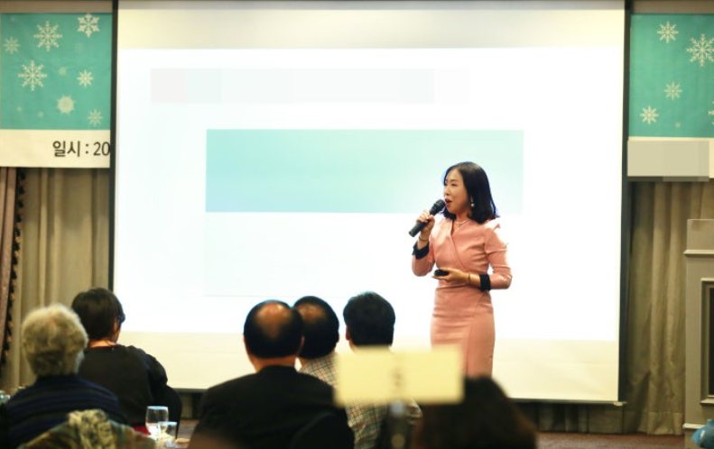 행사장에서 마이크를 들고 힐링 강의를 하는 고아라 웃음치료 강사
